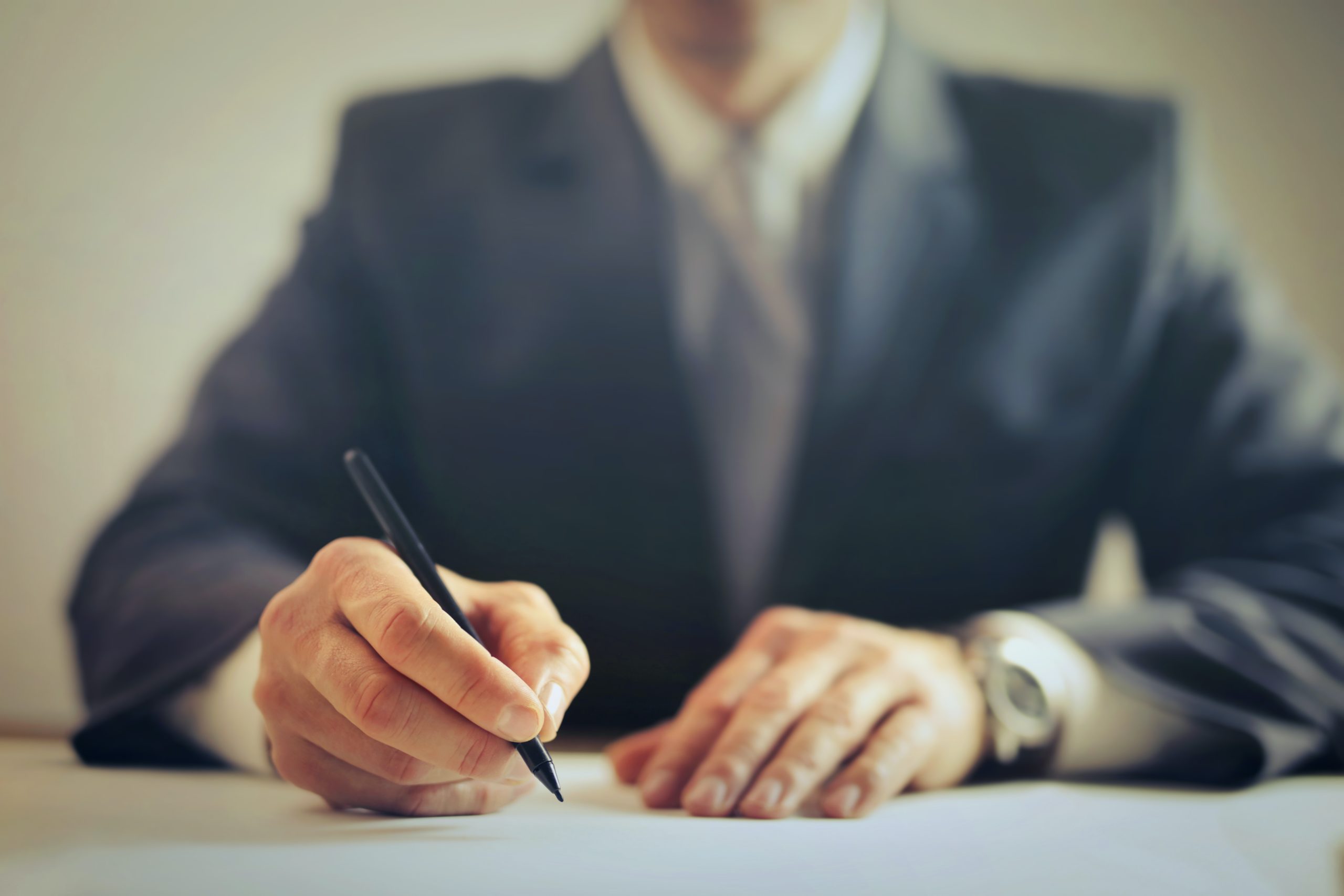 Man in suit sitting at table writing